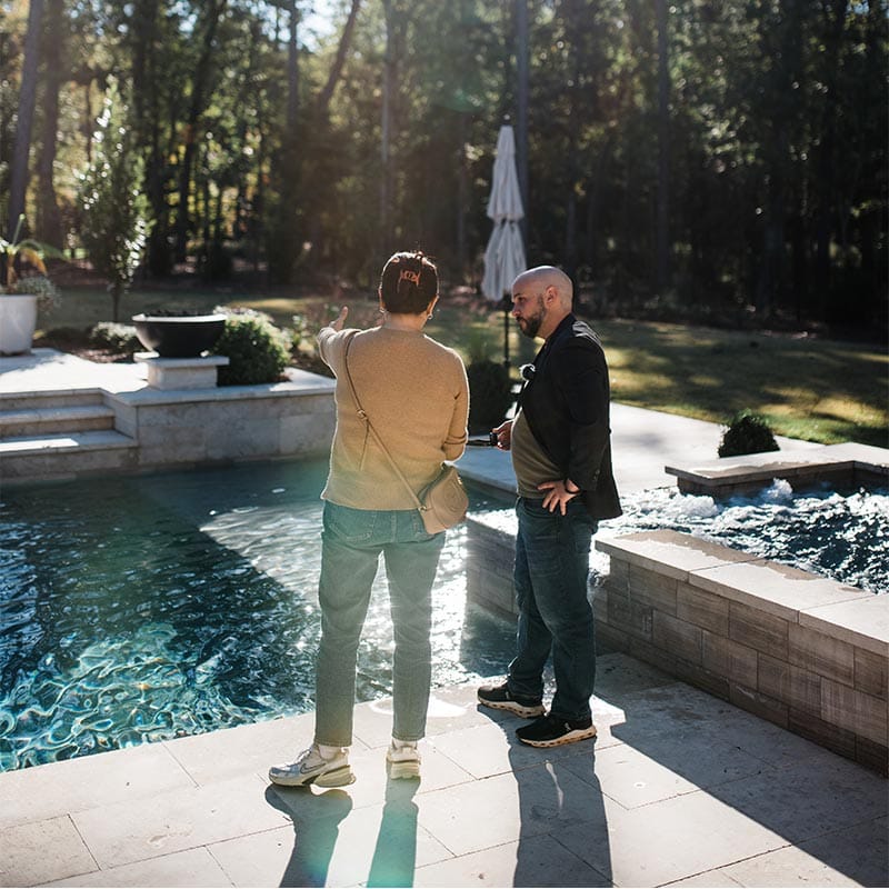 Chris Jones talking to client in front of concrete pool