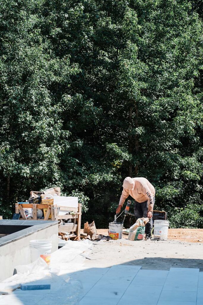 Worker handling concrete buckets with elevated pool on the left had side