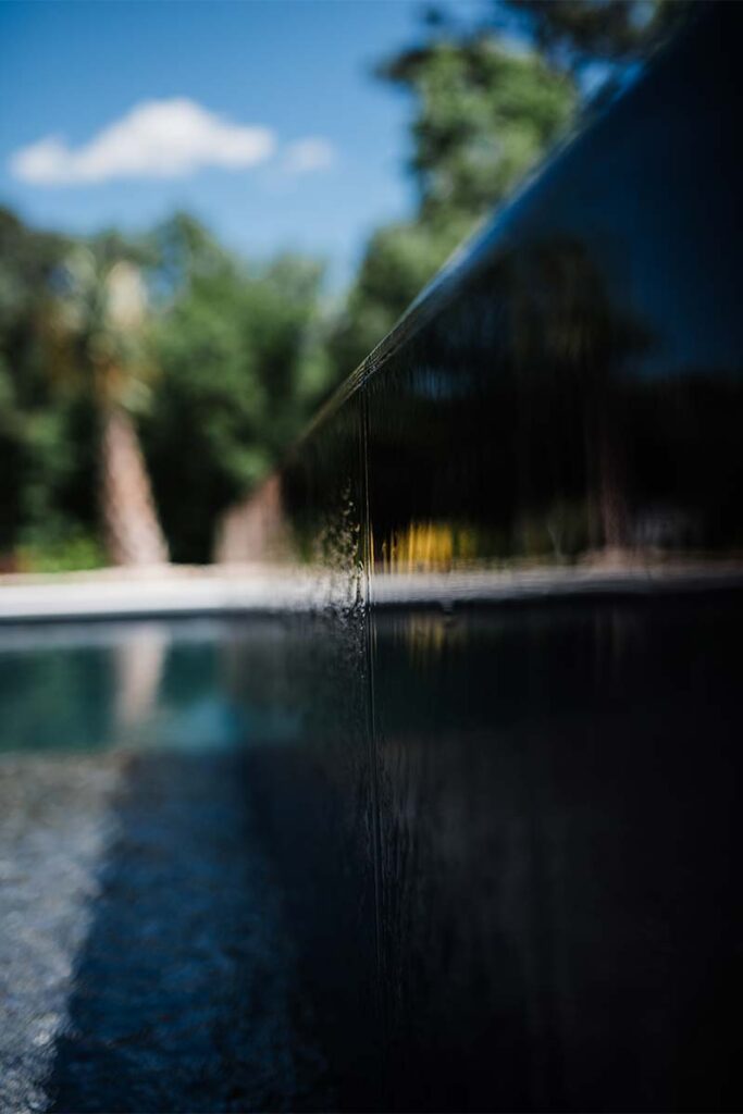 Extreme close up of elevated pool show casing water dripping into pool drainage system