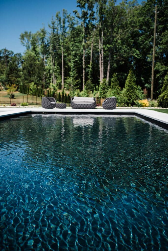 Drone over pool showcasing clear pool water with outdoor furniture around pool