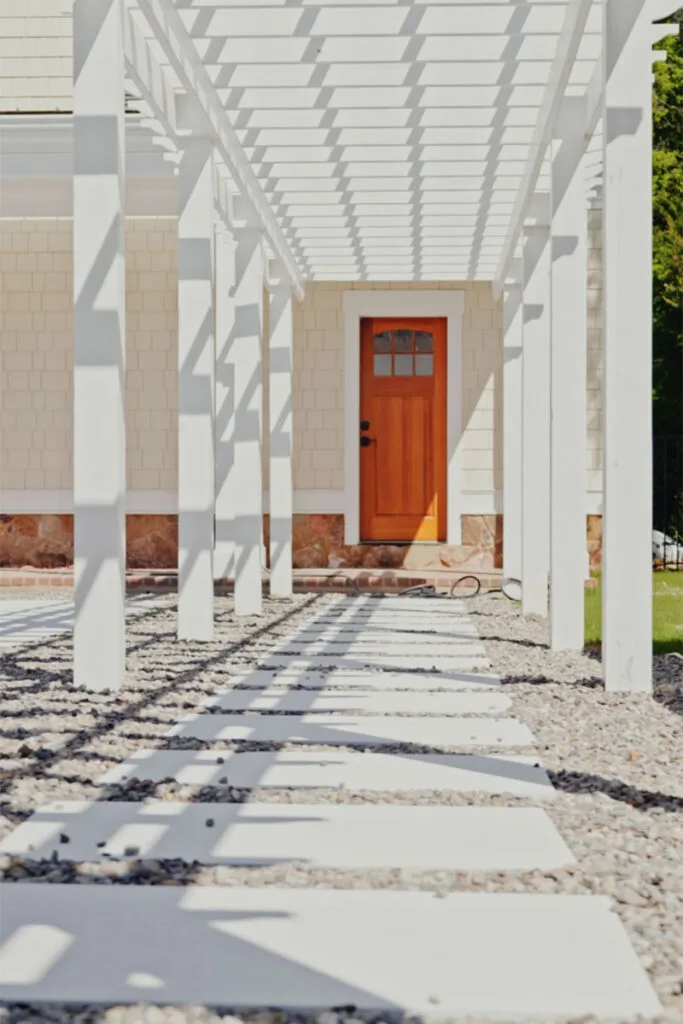 Front view of an orange door with walkways leading to with pergola