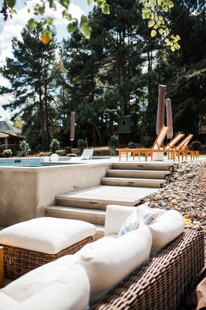Portrait of outdoor furniture in the foreground with steps leading to pool