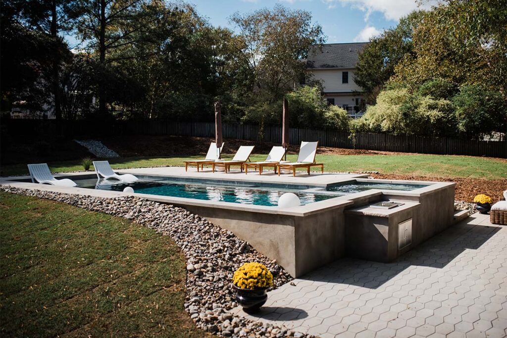 Concrete Cray with outdoor kitchen attached to concrete pool and spill over spa