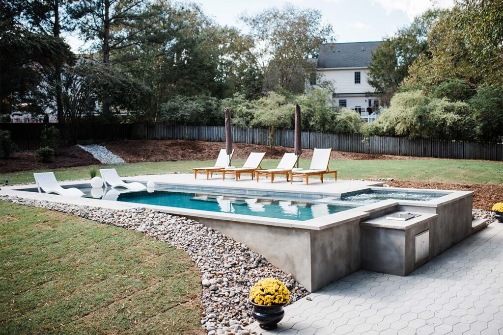 Concrete Cray with outdoor kitchen attached to concrete pool and spill over spa