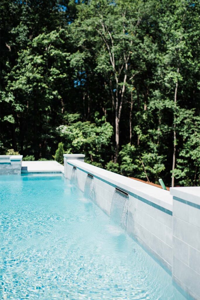 Formal Cary luxury pool with retaining wall and spill over spa