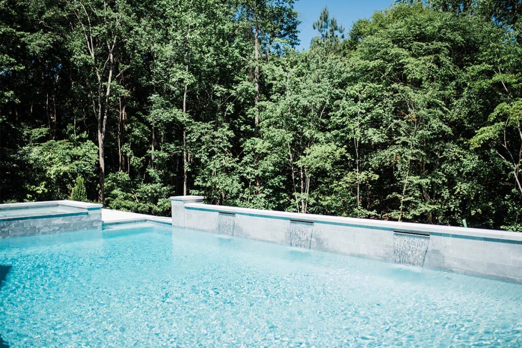 Formal Cary luxury concrete pool with retaining wall and spill over spa