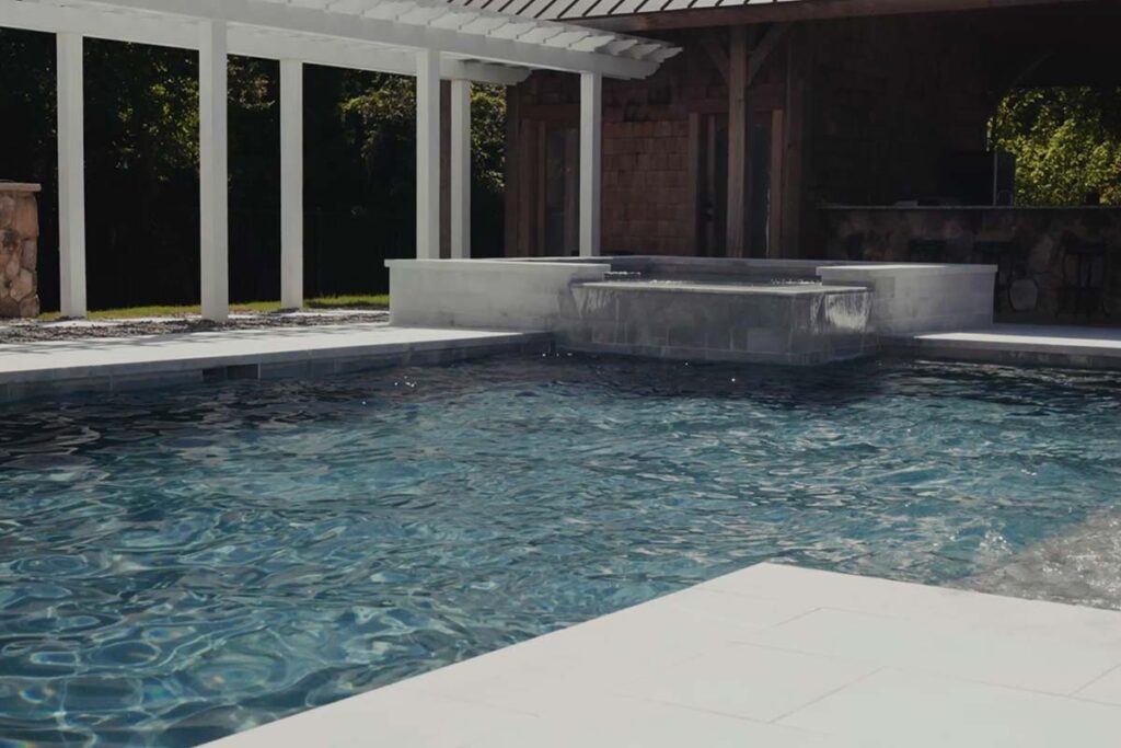 Front view of custom Concrete pool in Pinehurst NC. Pinehurst Contemporary features concrete pool with waterfall and corner spa